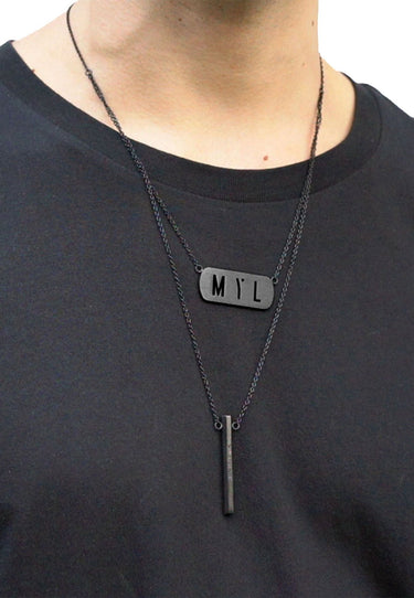 Unisex model wearing black Beacon necklace with engraved pendant and MYL tag, stainless steel dual-chain by MYL BERLIN.